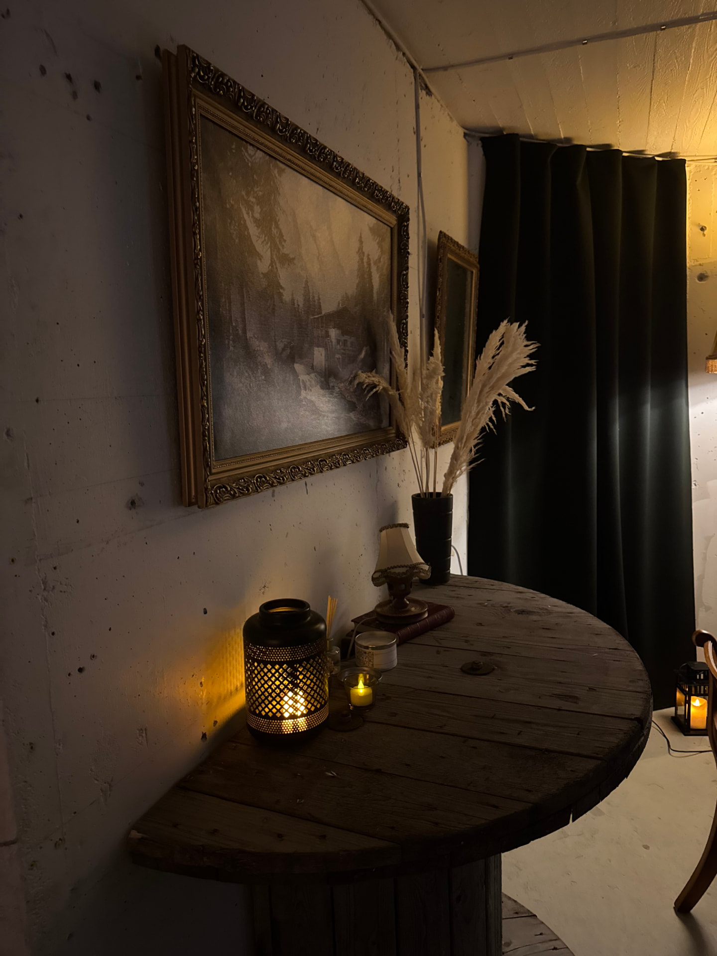 Hörn av skyddsrummet med tända ljus, antika tavlor och ett runt bord